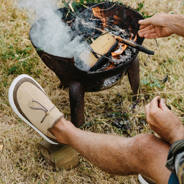 Beige slip on shoe with toe facing upper left beside a smoking charcoal grill outdoors