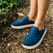 Navy slip on shoes facing left outdoors on a mulched garden path