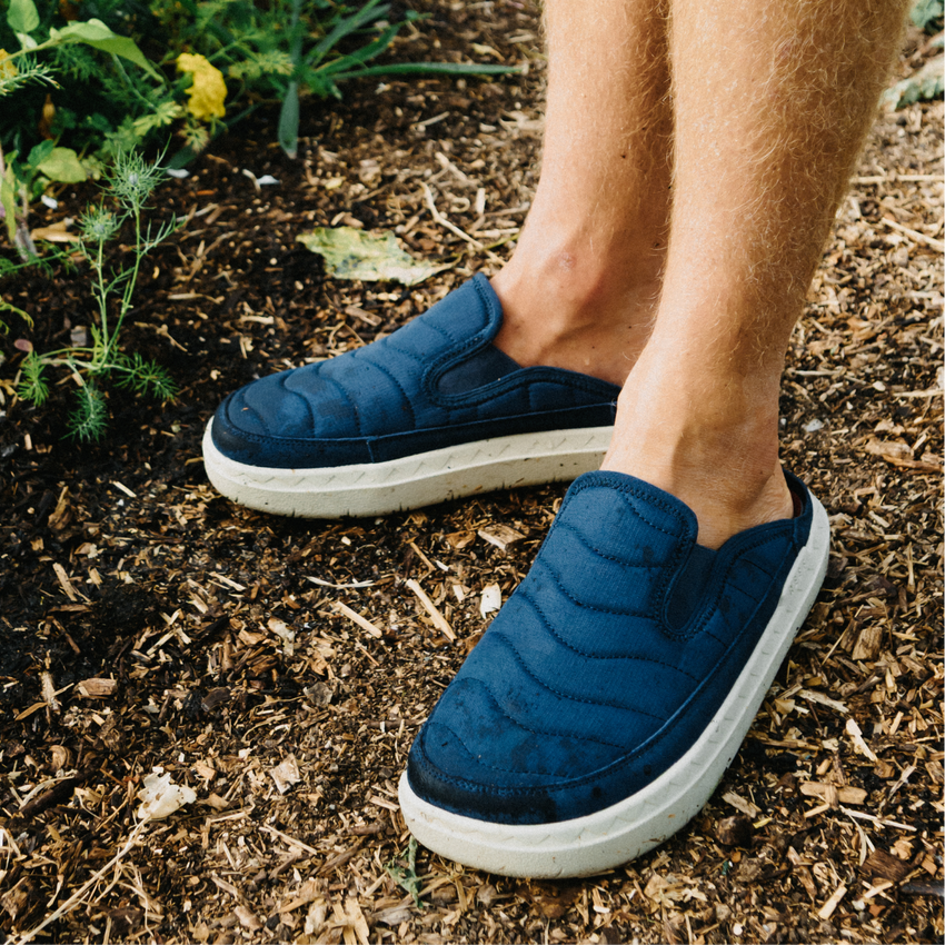 Navy slip on shoes facing left outdoors on a mulched garden path