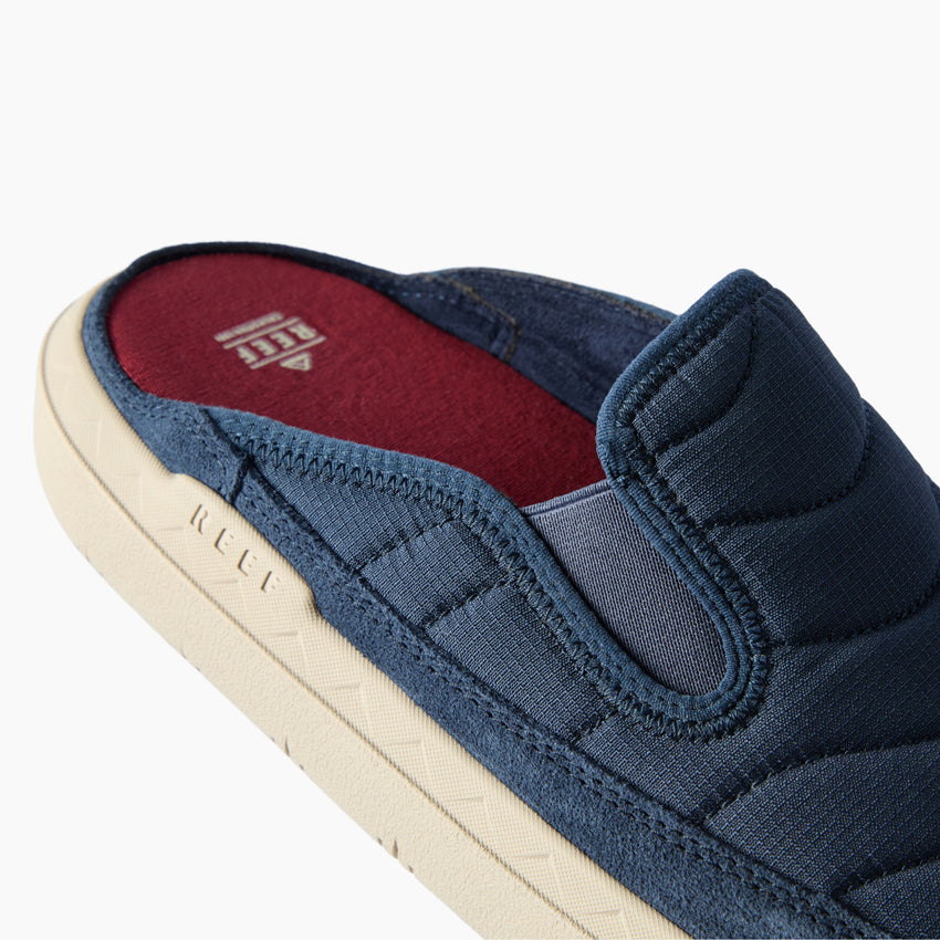 Close up of a navy slide facing left with a padded upper, red footbed, and cushioned cream sole