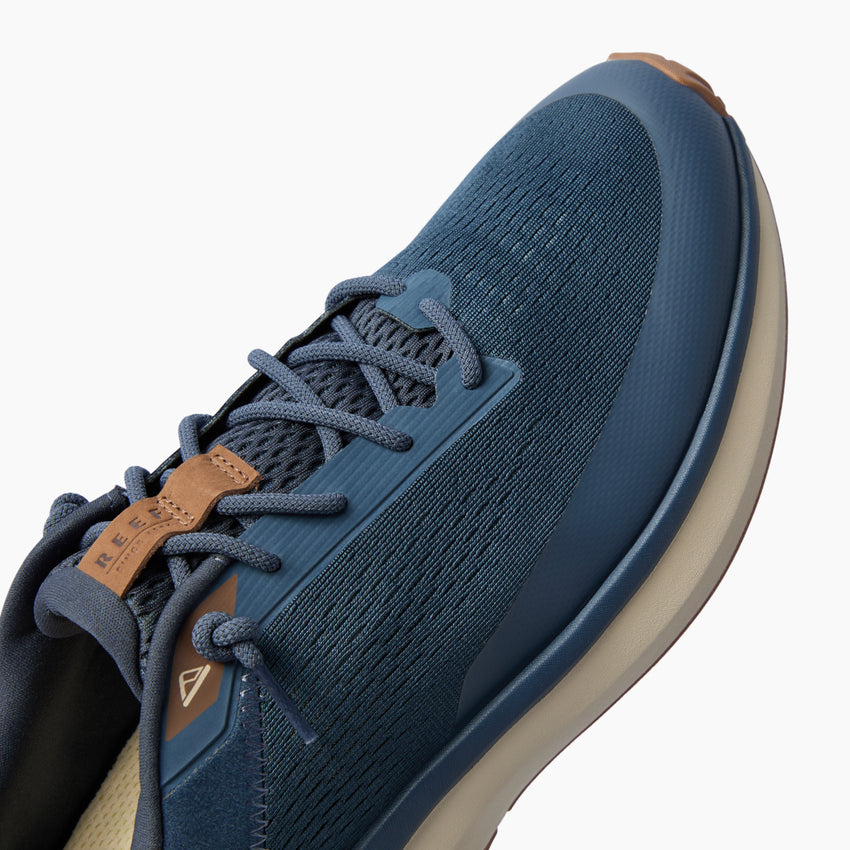 Reef Zuma blue sneaker close-up with toe facing upper right, showing knit upper and laces