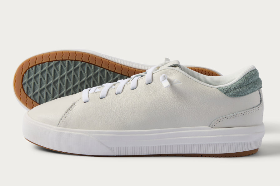 White low-top sneaker facing left with a gum outsole and gray heel accent.