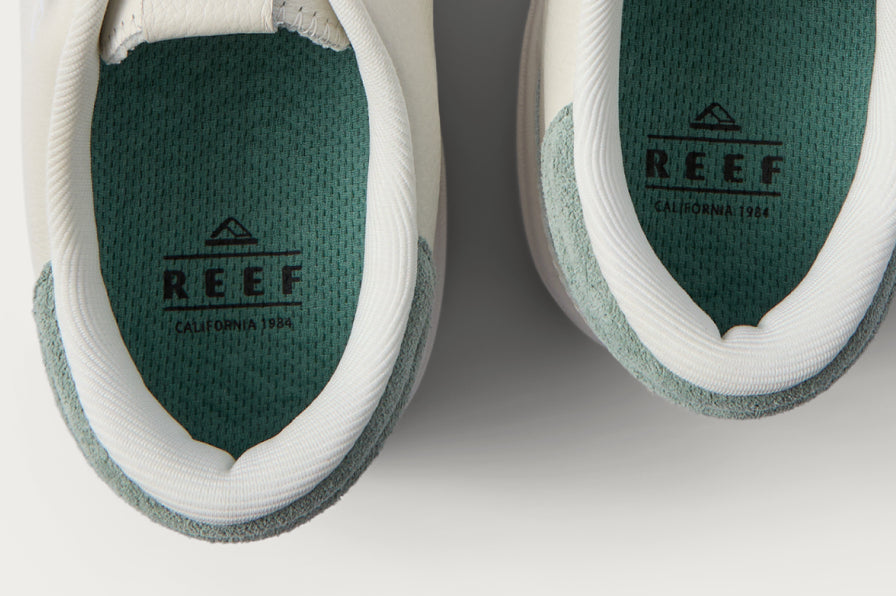 Close up of two REEF shoes facing upward showing heel openings and green branded footbeds