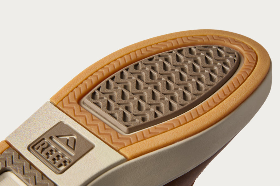 Close up of the underside of a REEF sandal facing upper right, with a textured durable outsole and logo