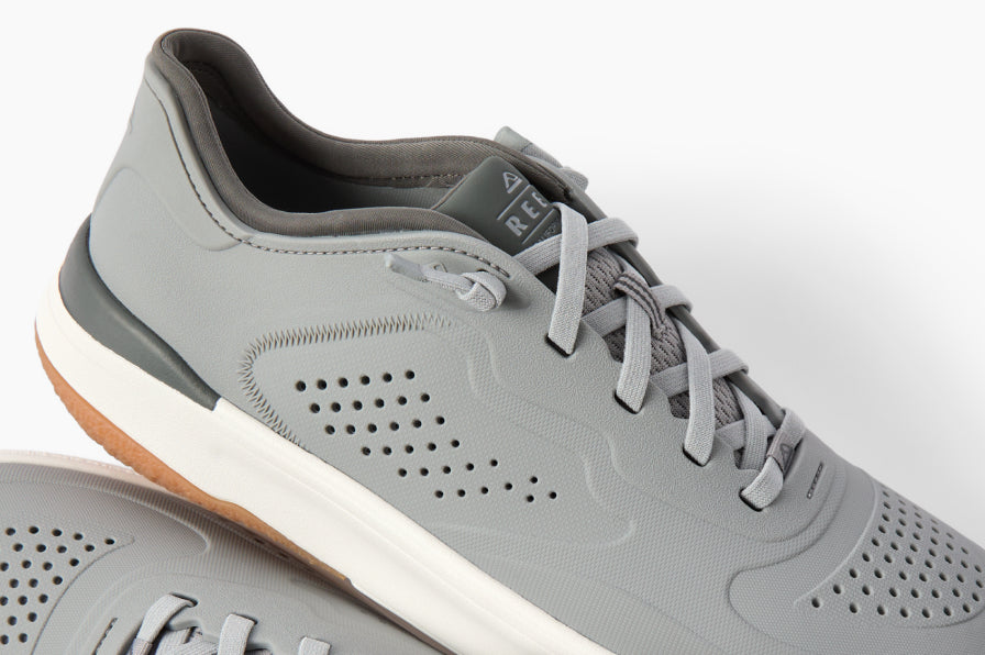 Close-up of grey sneaker facing right, featuring breathable perforations, cushioned collar, and durable rubber outsole.