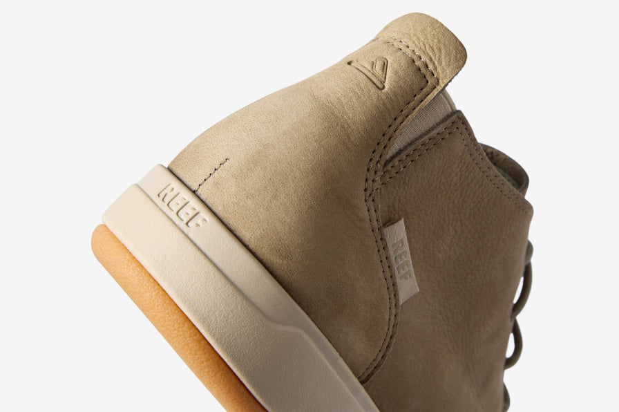 Close-up of a tan REEF high-top sneaker facing away, showing its padded heel collar and textured rubber sole.