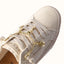 Lay Day Dawn x Jenny women's sneaker close-up on top showing soft neutral fabric, rope laces, and gold shell charm detail