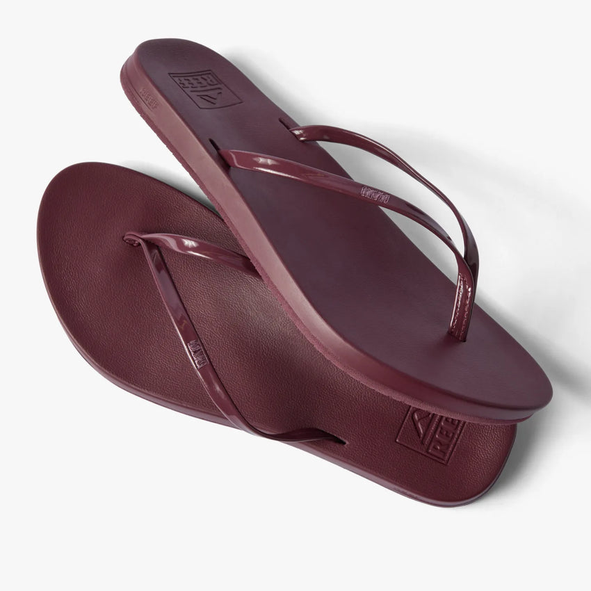 Pair of burgundy Cushion Slim flip flops with slim vegan leather straps shown from top and side angles, right facing sandal on top