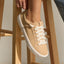 Close-up of a tan lace-up sneaker facing downward with white cushioned sole and side profile visible
