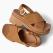 Brown platform sandals facing right and toward the viewer, with cross straps, buckle closures, and cushioned soles