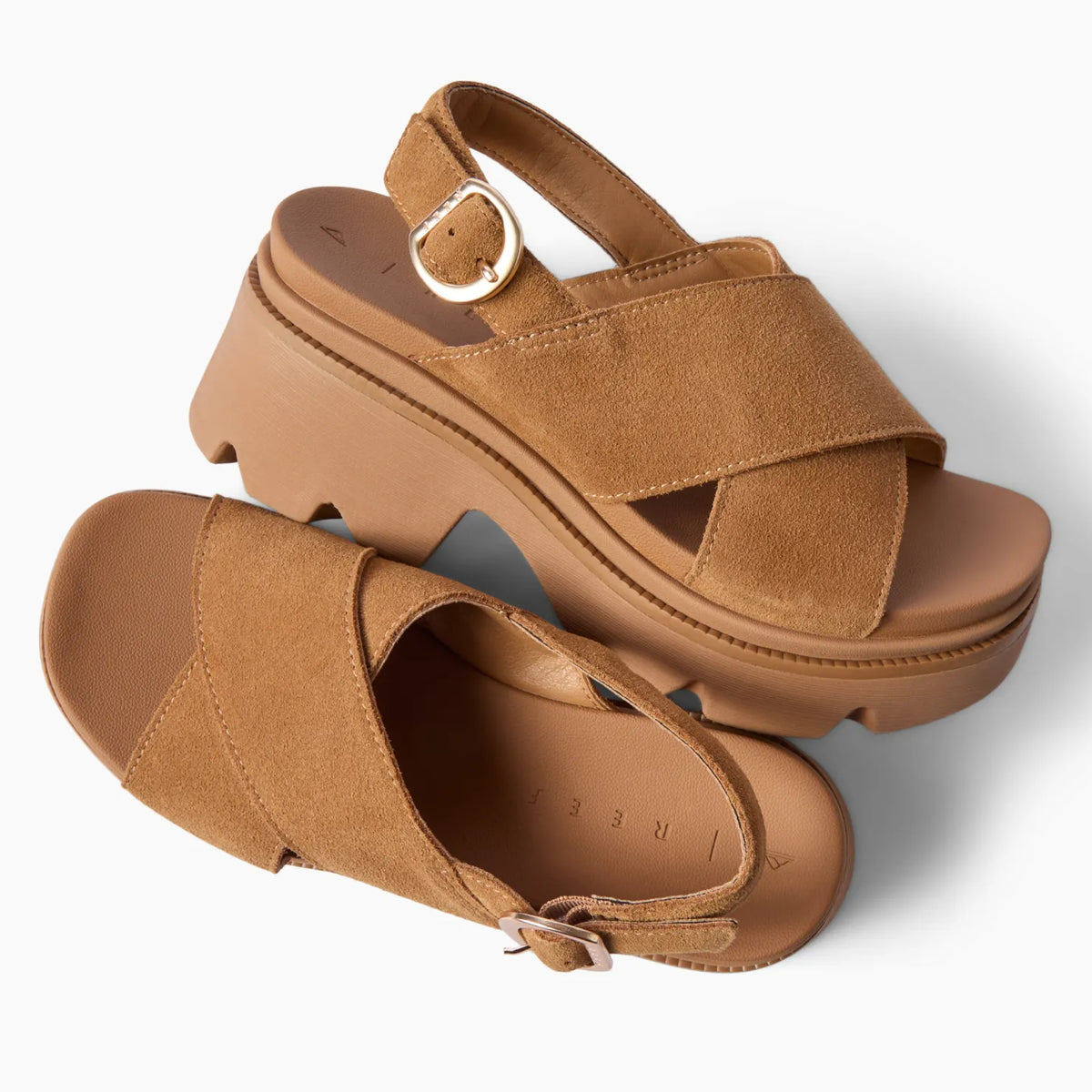 Brown platform sandals facing right and toward the viewer, with cross straps, buckle closures, and cushioned soles