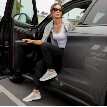 Reef Del Mar grey sneakers facing left as a woman steps from a car, featuring cushioned soles for comfortable everyday wear