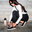 Neptune 2 black sneaker facing left, shown on a woman tying the laces for comfortable everyday wear