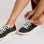 Neptune 2 black sneakers facing left with white laces being tied and cushioned soles visible