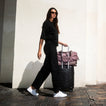 Neptune 2 white sneakers facing right as a traveler walks with luggage