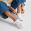 REEF Neptune 2 white sneakers facing toward the viewer as a woman ties the laces for everyday comfort