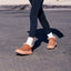 Tan fur-lined ankle boots facing left on a person walking in black leggings and white socks