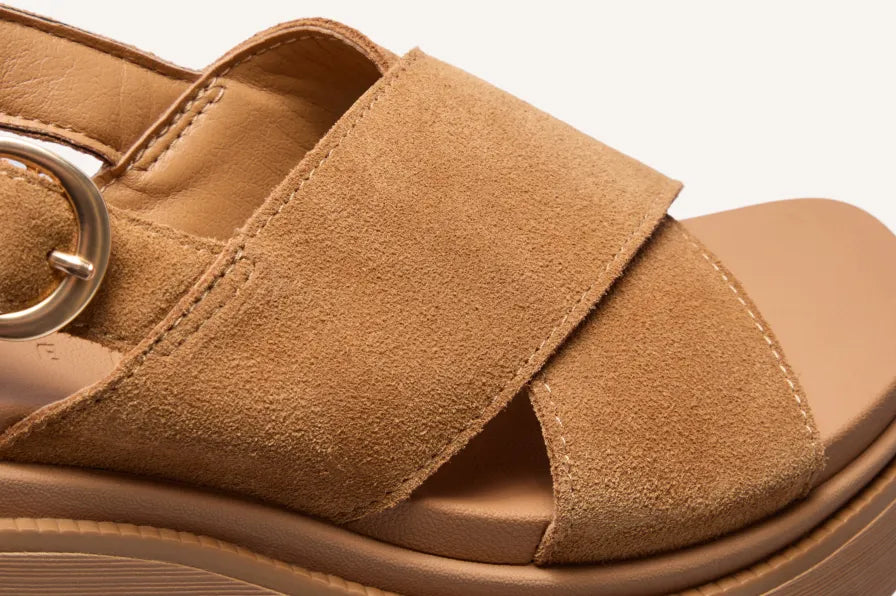 Close-up of a tan suede sandal facing right, showing overlapping straps and the open toe.