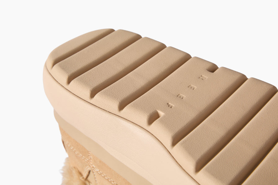Close-up of a tan sandal facing left, showing its textured outsole tread and cushioned footbed