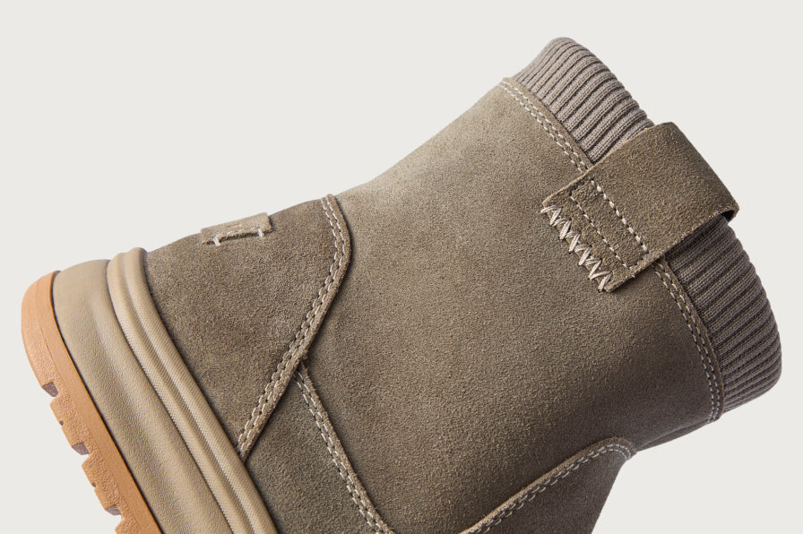 Close up of a taupe ankle boot upper and ribbed collar facing left