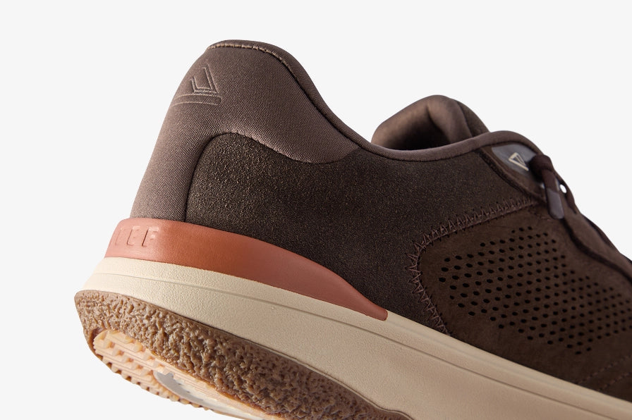 Close-up of a brown sneaker facing right, showing a perforated side panel, padded collar, and textured sole