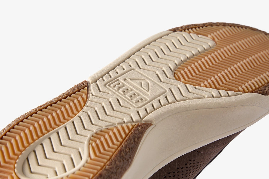 Close-up of a shoe outsole facing the viewer, showing textured tread and REEF logo