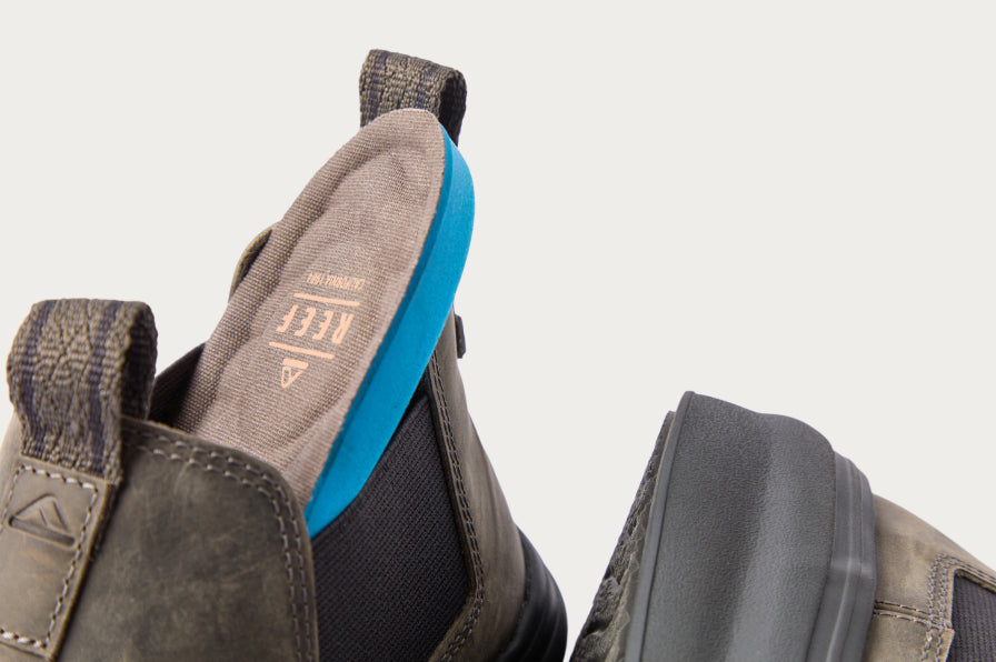 Close-up of the back and heel of gray REEF boots with blue cushioned insoles, highlighting comfort and arch support features.