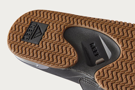 Close-up of the bottom sole of a left REEF shoe facing upward, showing textured tread and logo details.