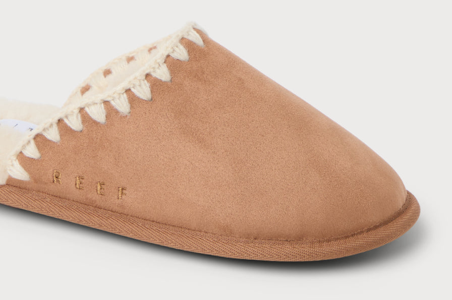 Close-up of the left front of a tan slip-on clog with suede upper, stitched trim, and soft plush interior lining for comfort.