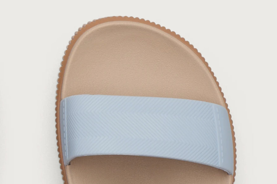 Top view of tan slide sandal with light blue strap and textured edge, designed for beach comfort and all-day wear.