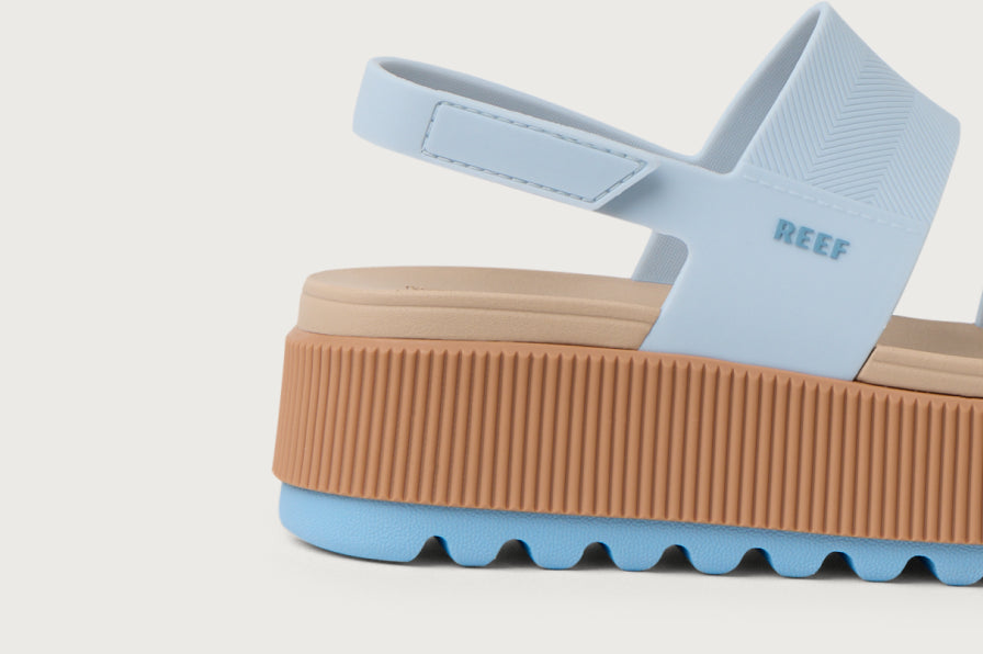 Side view of light blue and tan platform sandal showing textured sole and back strap with REEF branding embossed