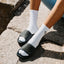 Phantom Slab black slides facing left on a person wearing white socks with cushioned comfort