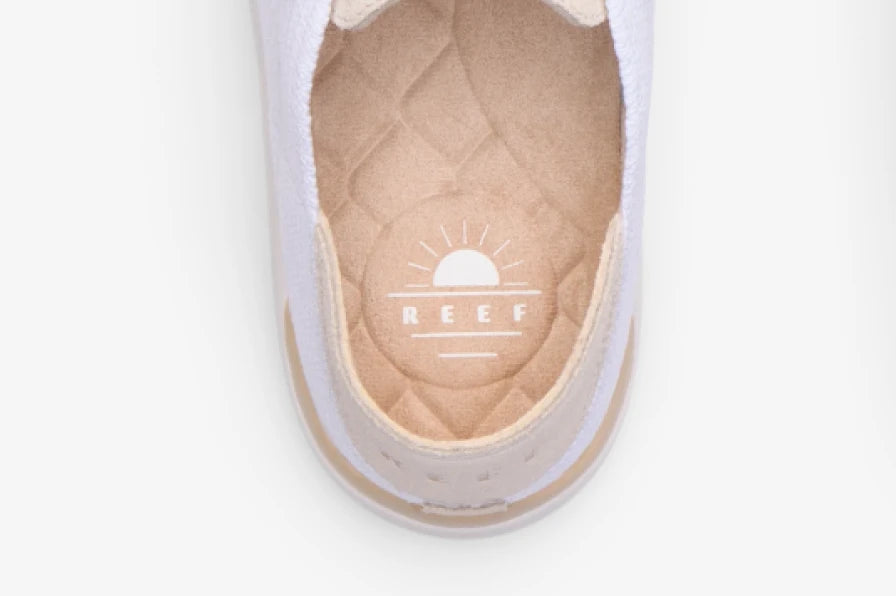 Top-down close-up of a white REEF shoe facing upward, showing its quilted cushioned footbed and heel logo