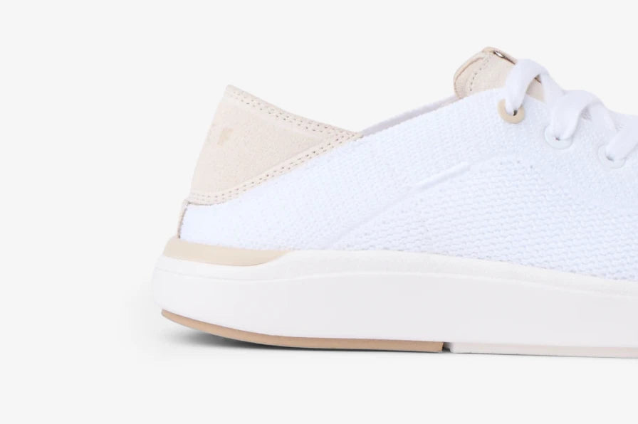 Close-up of a white sneaker facing right, showing the heel, textured upper, laces, and cushioned sole.