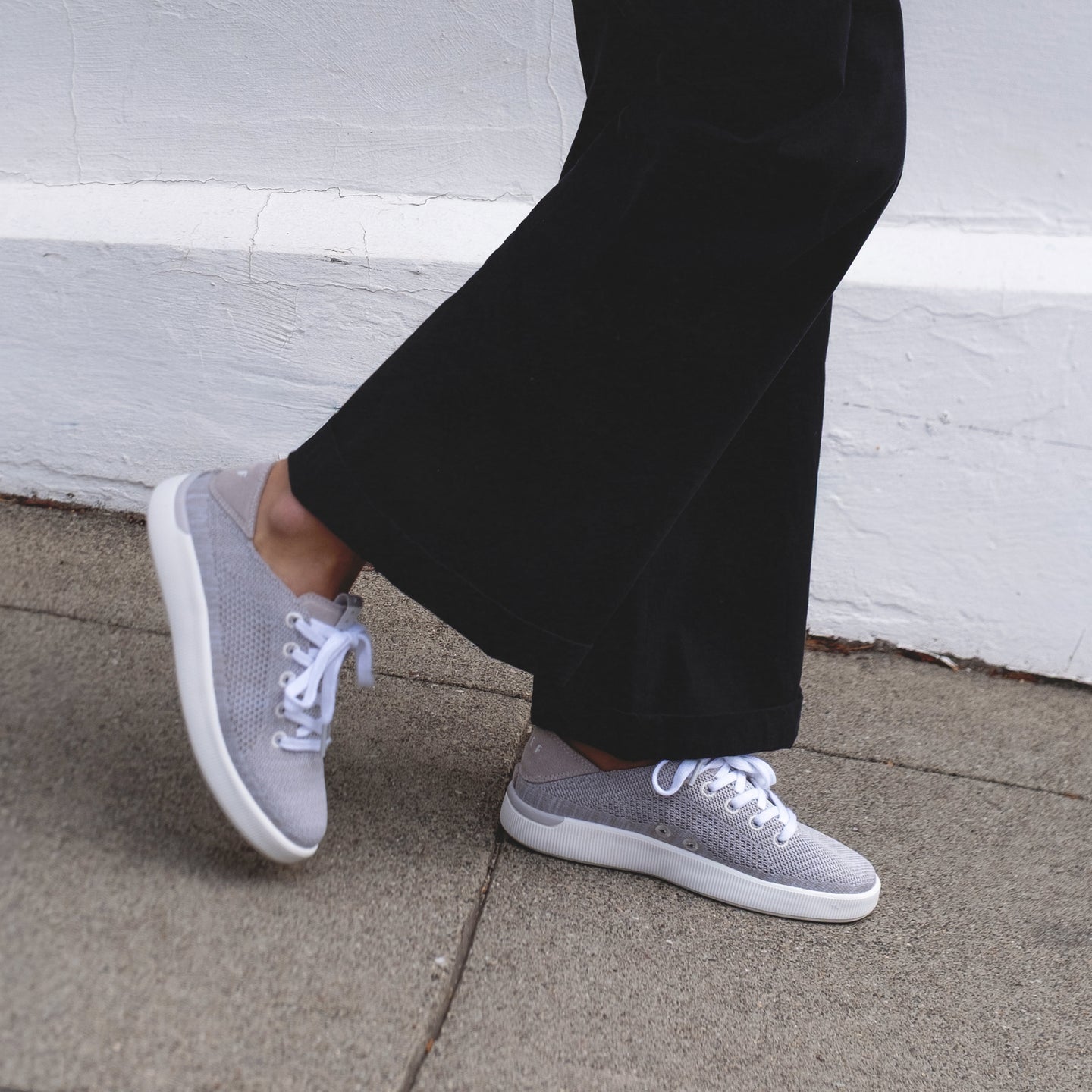 Side view of Reef Neptune lightweight grey women's sneaker with breathable knit upper and cushioned sole on a sidewalk.
