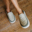 Rambler Kicker cream slip on mules facing toward the lower right on a wood floor