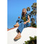 Woman sitting outdoors wearing tan Cushion Vista Hi sandals facing left with arch support and soft cushioning visible