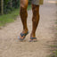 Men's feet wearing Cushion Phantom 2.0 flip flops walking on sandy path, right foot forward, showing top and side view.