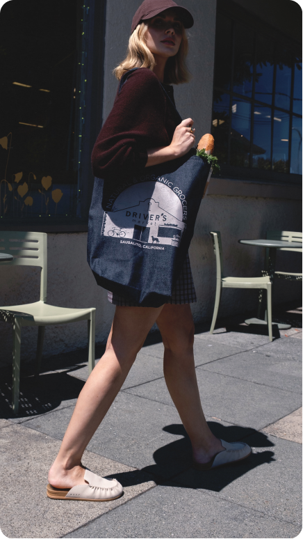 Side view of person walking on sidewalk wearing blush pink slip-on clogs with cushioned sole and low profile heel