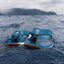 Close-up of blue Deckhand sandals facing forward on water, featuring molded footbeds and surf-inspired comfort design.