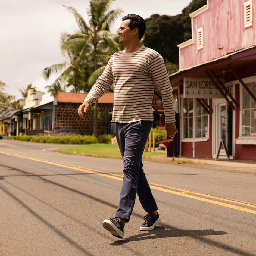 Man walking on street wearing Atlantic shoes facing right, featuring comfort and surf-inspired design in navy and cappuccino colors.