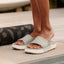 woman wearing Sydnee Cutback Low Sage slide next to yoga mat