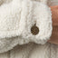 Close-up of sleeve cuff with metal button featuring REEF logo on cream Sammie Sherpa Jacket for women, surf-inspired comfort apparel.