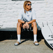 Tailslide men's tan slides with toes facing the camera on a seated model beside a surfboard