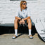Tailslide men's tan slides with toes facing the camera on a seated model beside a surfboard