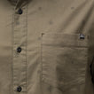 Close-up of the olive green Topaz Shirt pocket with subtle dot pattern and black buttons, beach-inspired comfort apparel.