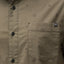 Close-up of the olive green Topaz Shirt pocket with subtle dot pattern and black buttons, beach-inspired comfort apparel.