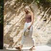 Woman walking right wearing brown Cushion Vista Hi sandals, showcasing lightweight beach-inspired comfort and arch support.
