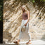 Woman walking right wearing brown Cushion Vista Hi sandals, showcasing lightweight beach-inspired comfort and arch support.
