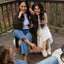 Two women wearing Vista Skye slip-on shoes seated on a deck, right shoe facing forward, left shoe angled slightly outward.